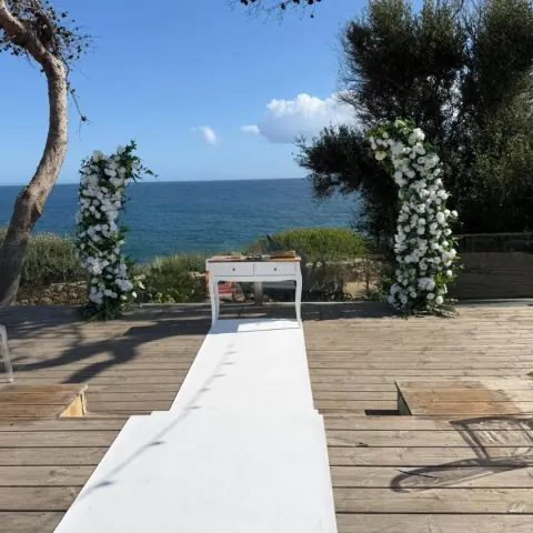 Caminho branco até ao altar, entre flores e árvores, com o mar de Cascais ao fundo