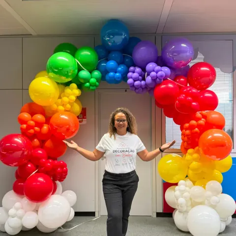 Cibele apresenta um arco de balões com as cores do arco-íris num workshop